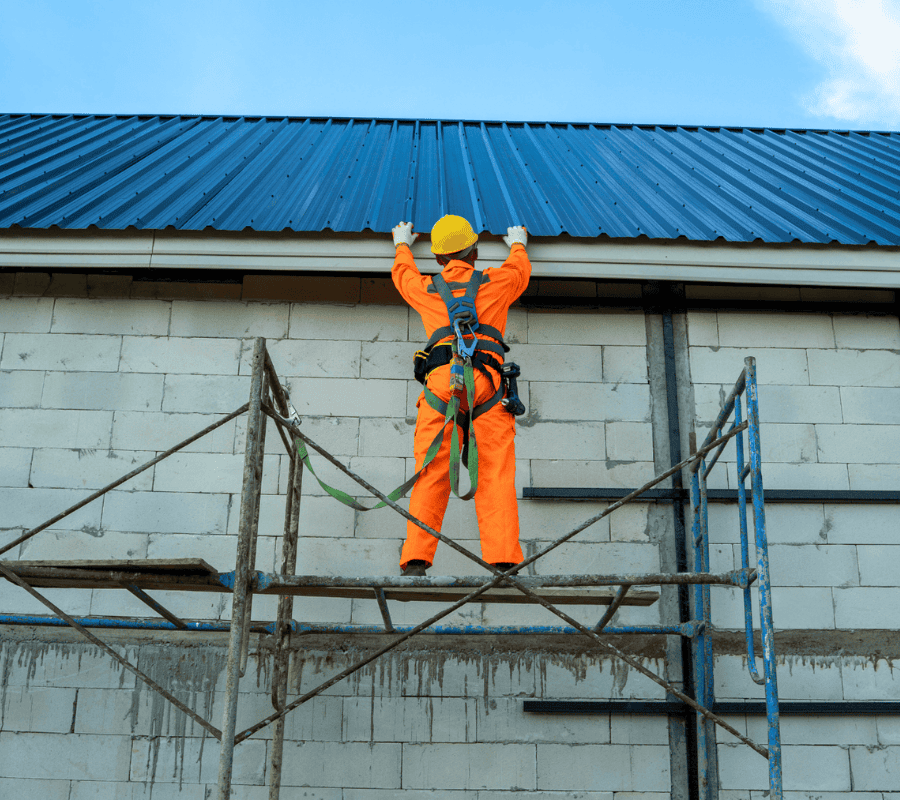 Man in high-visibility clothing standing on scaffolding.